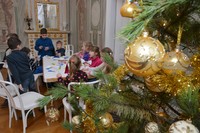 Fragment choinki w pałacu mieroszewskich, w tle dzieci przy stołach na warsztatach