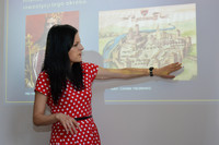 agnieszka milka z działu edukacji stojąca przez prezentacja multimedialna i opowiadająca o warsztatach muzealnych