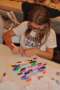 dziewczynka podczas warsztatów, siedząca przy stole i wykonująca prace plastyczne