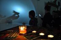 Andrzejki- zdjęcie dziecka trzymajace woskową figurę pod lampą i na scianie widać cień figury